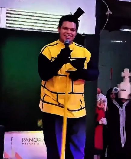Aluno autista sorrindo enquanto canta no palco durante apresentação