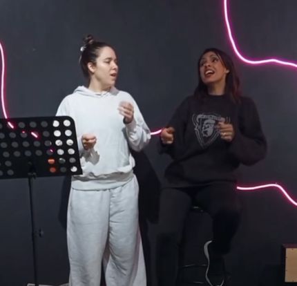 Aula de canto em andamento, aluna e professora cantando pop rock
